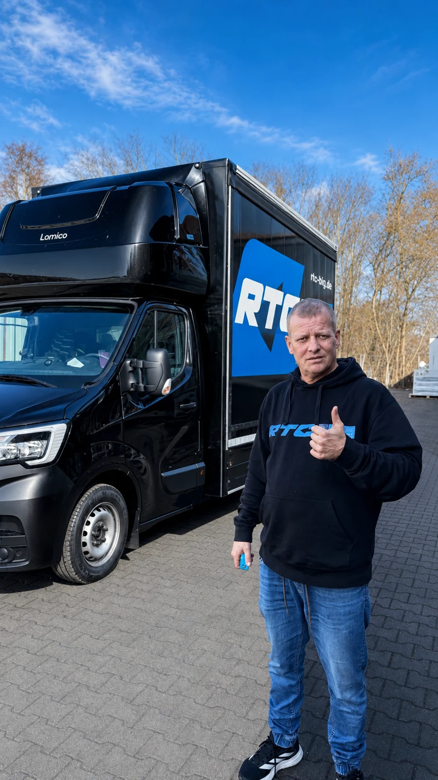 Lächelnder RTC-Mitarbeiter vor einem Transporter am Standort